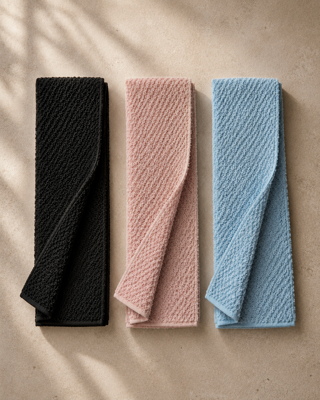 Black, pink and blue Kuyona towels arranged together on warm stone